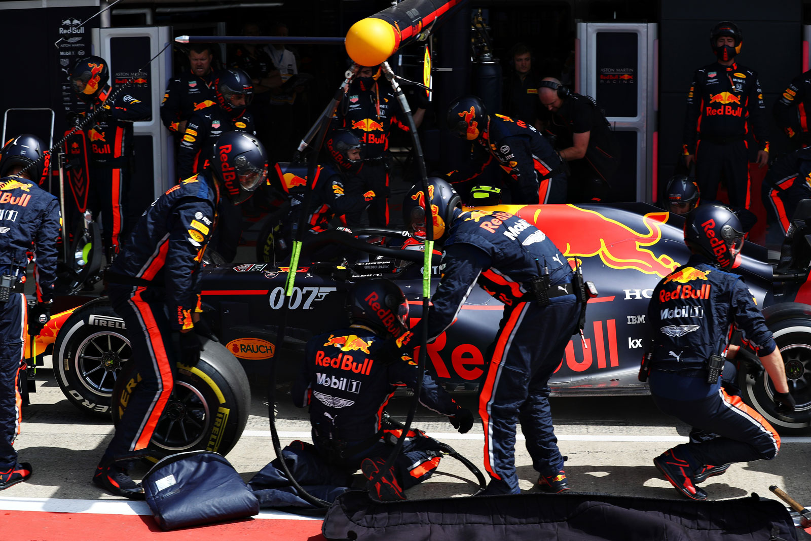 Multiple Red Bull mechanics work to perform a pit stop during a race